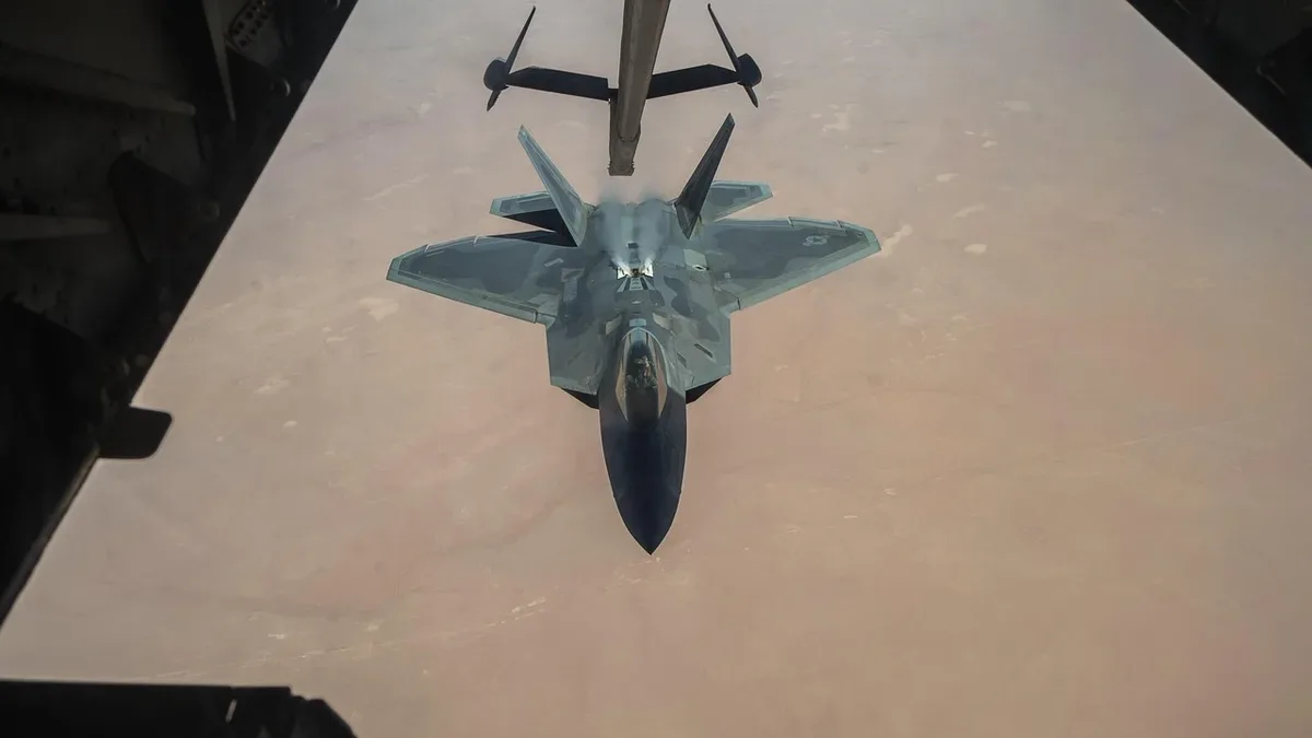 A fighter jet flying in the sky, with its shadow visible on the ground below.